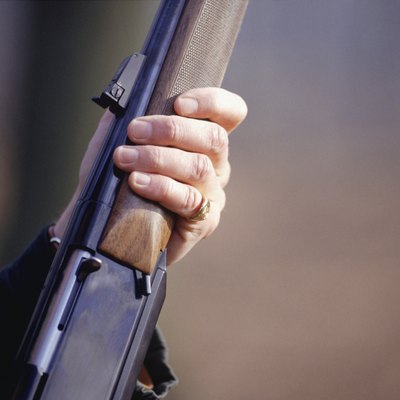 Man holding shotgun, mid section, close-up of hand