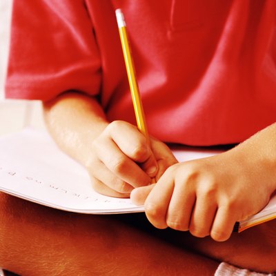 close up of a child's (8-10) hands writing in a notebook