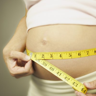 Cropped pregnant woman measuring waist