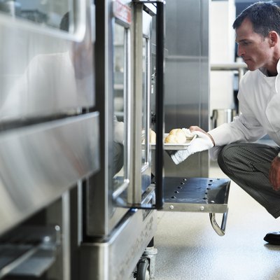 Chef taking food from oven in restaurant kitchen