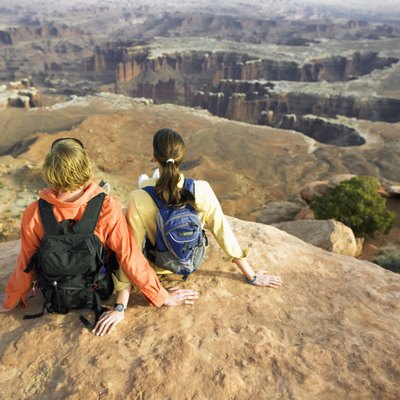 Young couple with backpacks sitting on rock