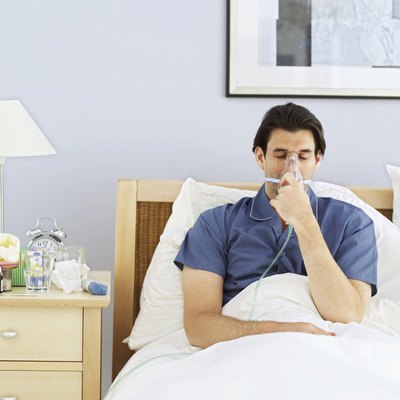 Young man lying in bed wearing an oxygen mask