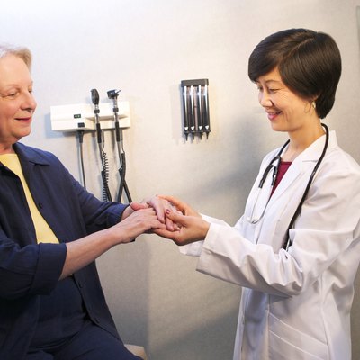 A doctor examines a mature woman's arm in the doctor's office