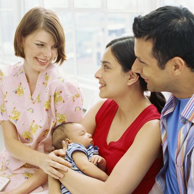 mid adult woman smiling and looking at a mid adult couple holding their son