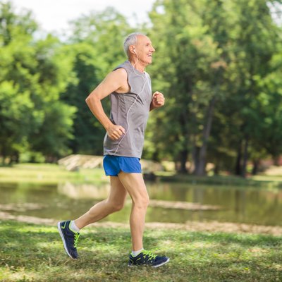 Active senior jogging in a park and listening to music