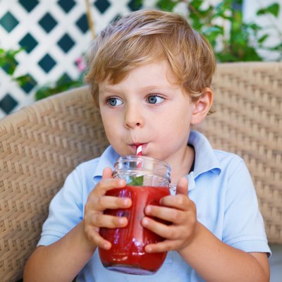 Little blond boy drinking healthy watermelon juice in summer.