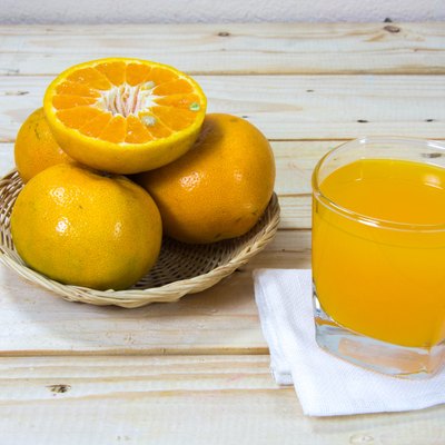 Glass of orange juice and slices of orange on wooden