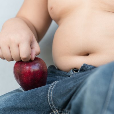 Fat boy pick up red apple, as concept of diet.