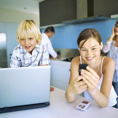 Close-up of two children in front of a laptop with their parents standing behind them