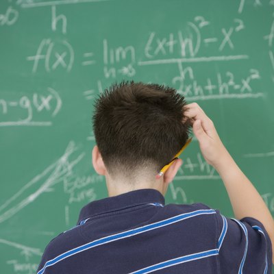 Hispanic boy scratching head in front of blackboard