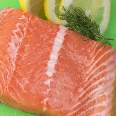 Salmon fillet on plastic cutting board with garnishes