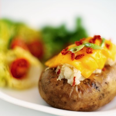 Close-up of salad and a baked potato with cheese and chives