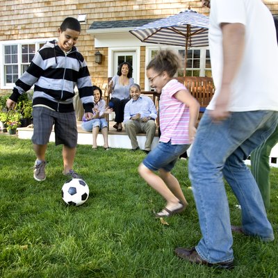 Family playing soccer in suburban backyard