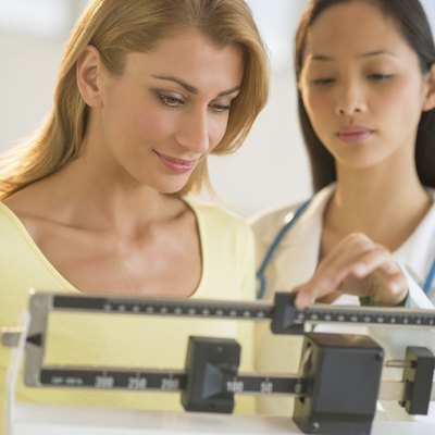 Doctor Weighing Woman On Balance Weight Scale