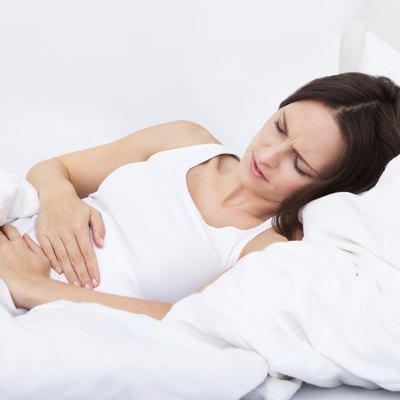 Woman with stomach ache lying on bed