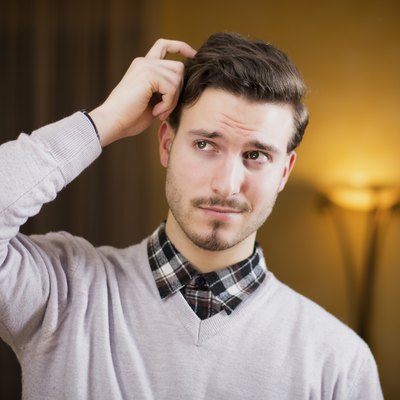 Confused or doubtful young man scratching his head
