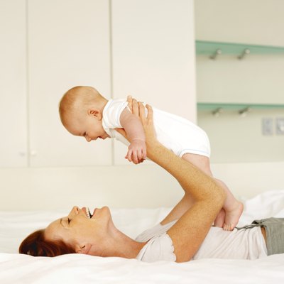 side view of a mother lying on a bed holding her baby (6-12 months)