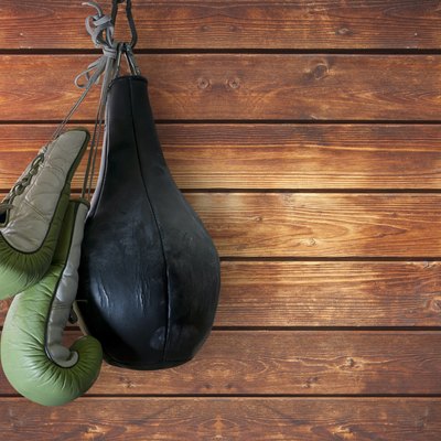 old boxing gloves and punching bag hang on wooden background