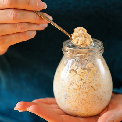 Woman's slender hands holding glass jar and spoon with overnight