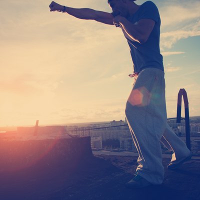 Young man boxing with shadow at sunset on the top of the roof in the city (intentional sun glare, lens flares and vintage color)
