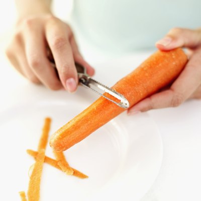 Close-up of a woman's hands peeling a carrot with a peeler