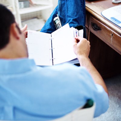 shot of a man sitting on a chair and looking through a diary