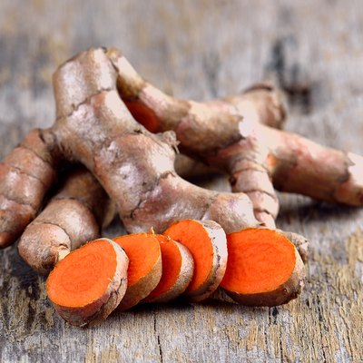 pile of fresh turmeric roots on wooden table