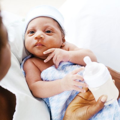high angle close-up of a woman feeding a baby with a bottle