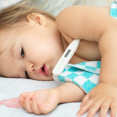 Baby ailing and lying with thermometer