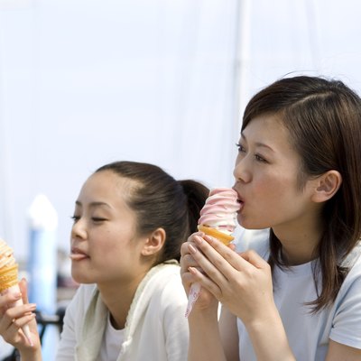 Two young Japanese women eating soft ice cream at port