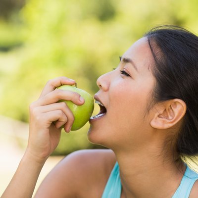 Healthy young woman eating apple in park