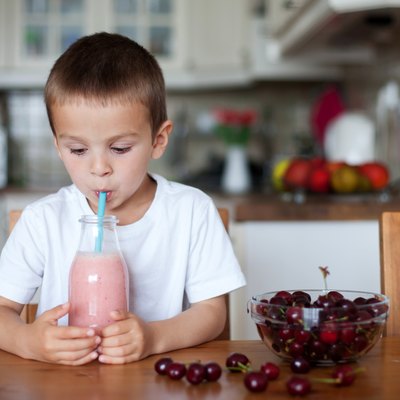 Happy school boy drinking a healthy smoothie as a snack
