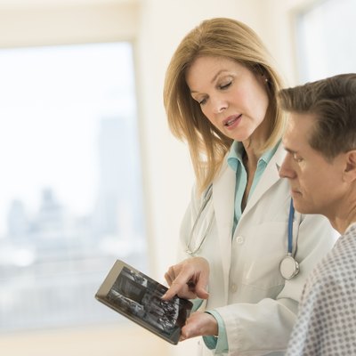 Doctor showing digital tablet to patient in clinic