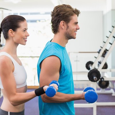 Fit couple exercising with blue dumbbells