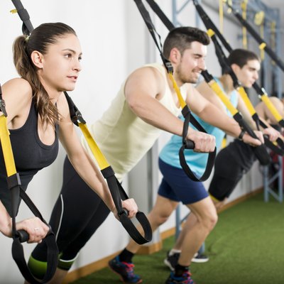 People at gym doing elastic rope exercises