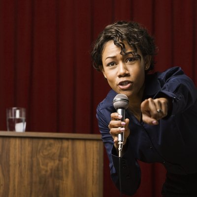 Mixed race businesswoman speaking on stage and pointing