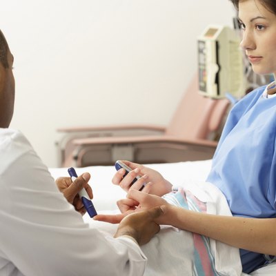 Rear view of a male doctor taking a blood sample from a female patient's finger