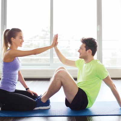 man with personal trainer doing sit ups in gym