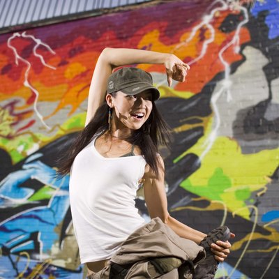 Woman street dancing by graffiti mural