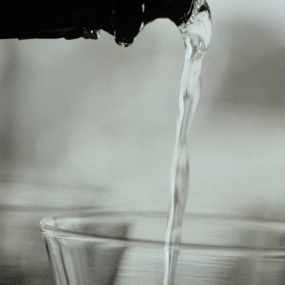 Liquid being poured from bottle to glass, close-up