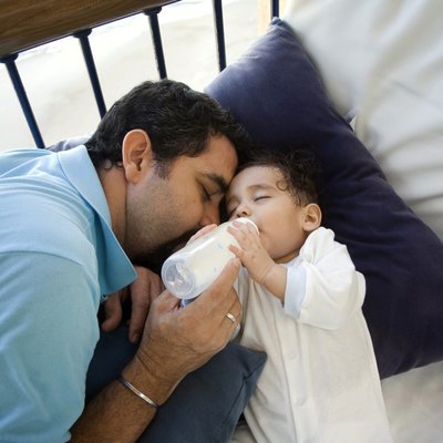 High angle view of a mature man feeding his baby with a bottle