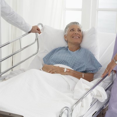Patient in hospital bed speaking to Doctor and Nurse, smiling