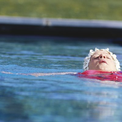 Woman floating on back in outdoor pool, surface view