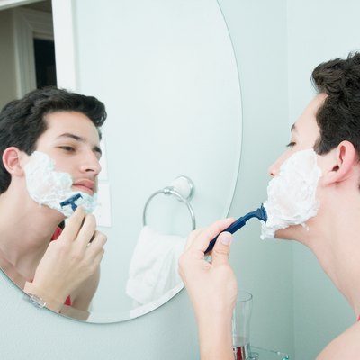 Boy shaving in mirror in bathroom