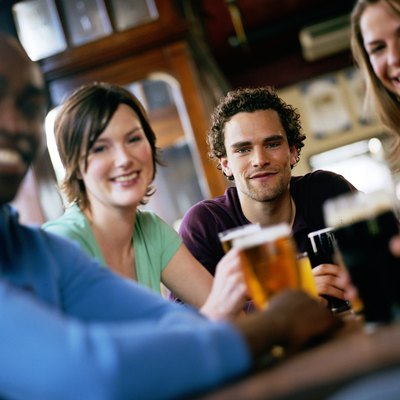 Friends at pub table, smiling, portrait (focus on man in centre)