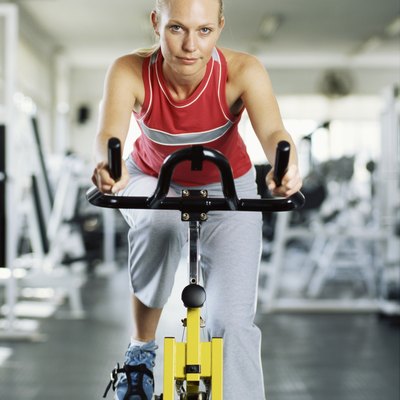 Portrait of a young woman on exercise bike in gym.