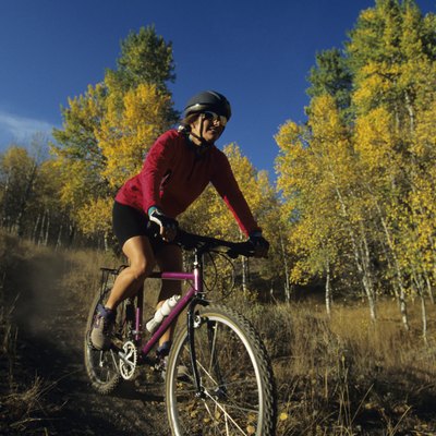 Female mountain biker riding on trail in forest