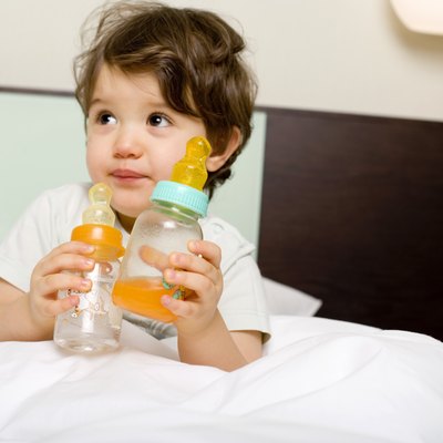 Child with baby bottles in bed