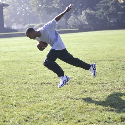 Teenage boy running with football in park