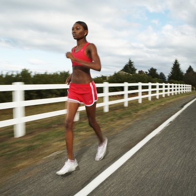 Young woman jogging along country road (blurred motion)